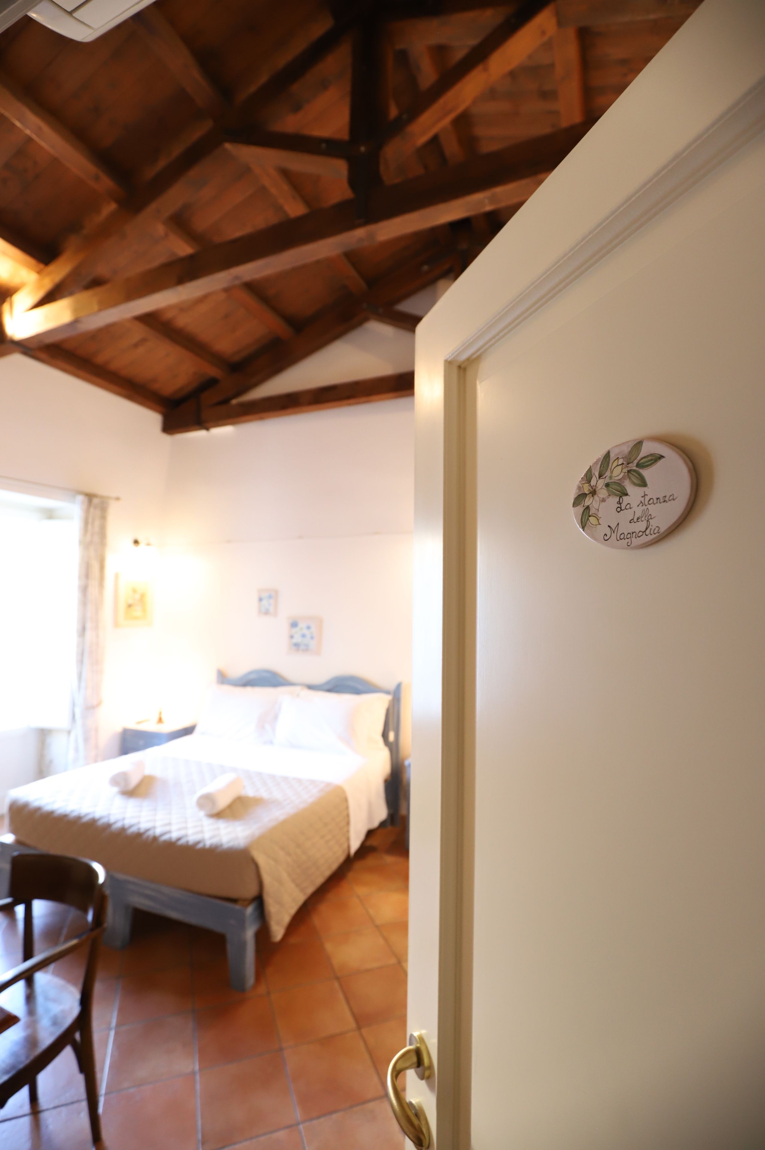 A bedroom with a bed, a chair, and a wooden ceiling.