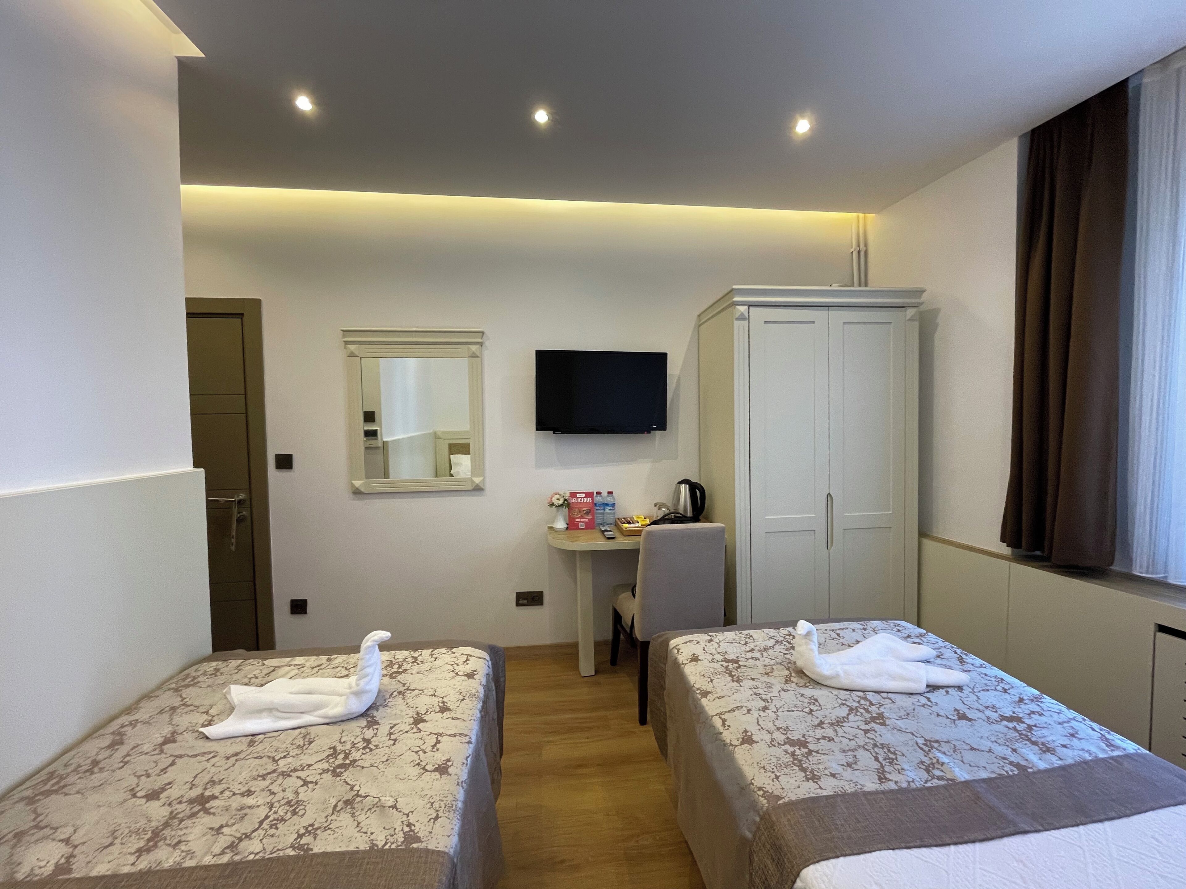 A hotel room with two beds, a desk, a television, and a wardrobe.