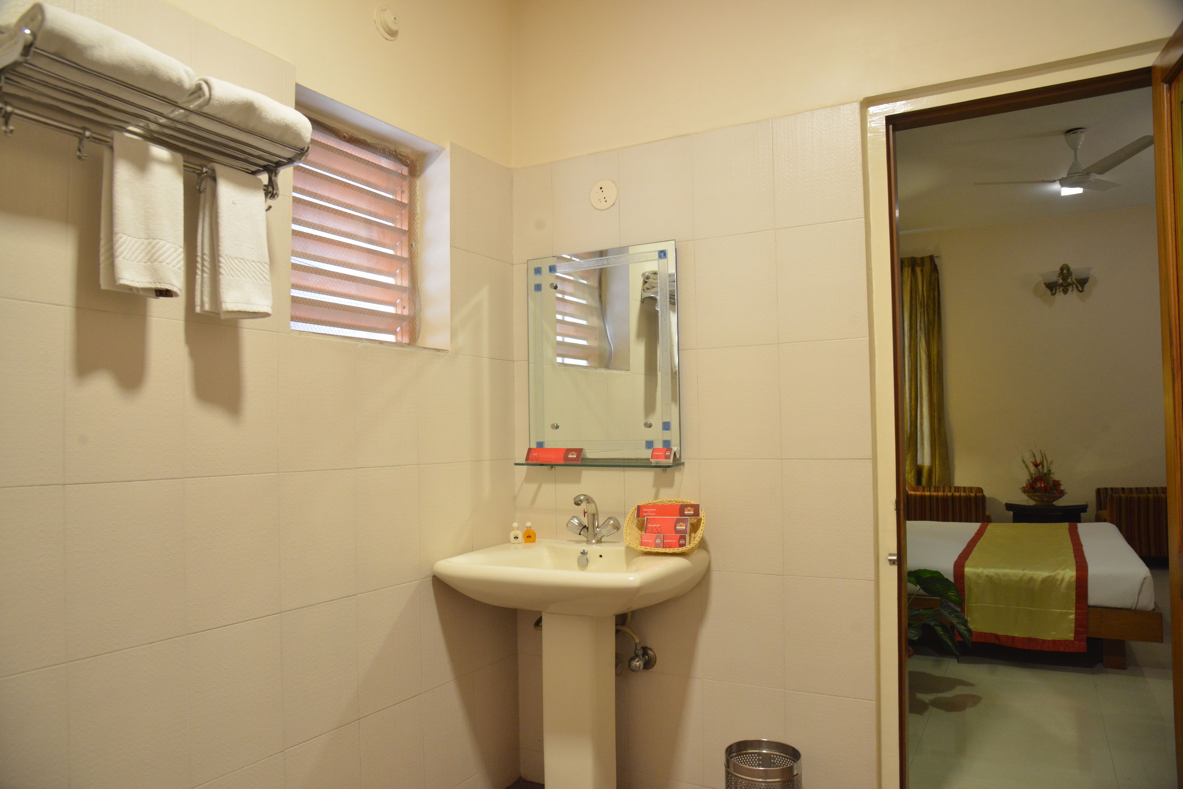 Un baño con lavamanos, espejo y toallas en un perchero.