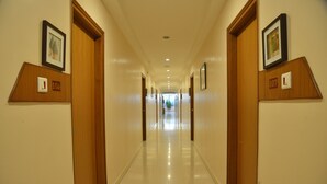 Un pasillo de hotel con puertas de madera, carteles con números y cuadros en las paredes.