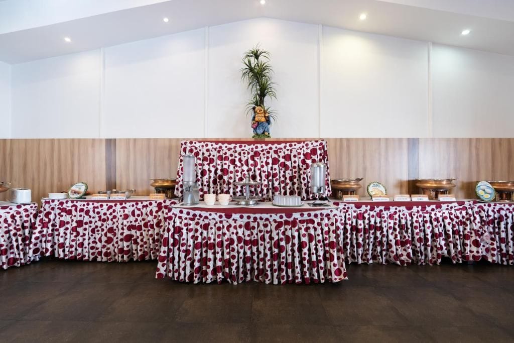 A banquet hall with a long table covered in a polka dot tablecloth, surrounded by chairs and a central decorative piece.