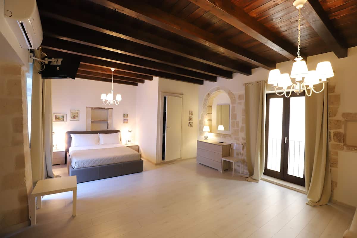 A bedroom with a bed, bedside table, dresser, and a chandelier.