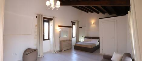 A bedroom with a bed, a bedside table, a dresser, a mirror, and a hanging light fixture.