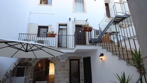 Un patio con un arco de piedra, mobiliario exterior, una escalera y plantas en macetas.
