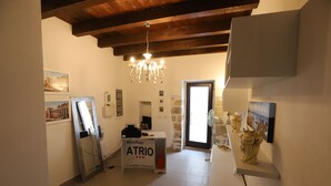 Un vestíbulo de hotel con mostrador de recepción, una araña, obras de arte en las paredes y una puerta que da al exterior.