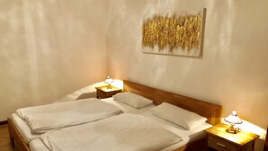 A double bed with white linens, two bedside tables with lamps, and a wooden headboard.