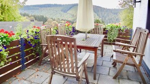 An outdoor patio with wooden furniture, a table, and an umbrella.
