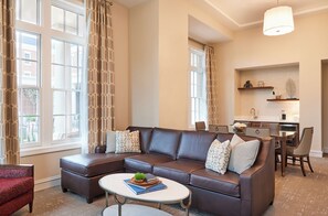 A modern living room with a sectional sofa, a coffee table, and a dining area with a kitchen in the background.