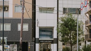 Un edificio de varios pisos con un diseño arquitectónico moderno, que presenta una combinación de estilos de ventanas y balcones.
