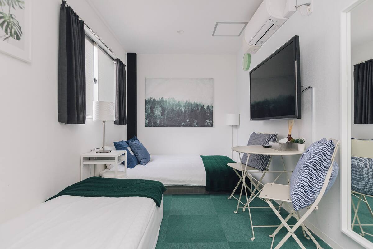 A hotel room with a bed, a desk, a chair, a TV, and a window with curtains.