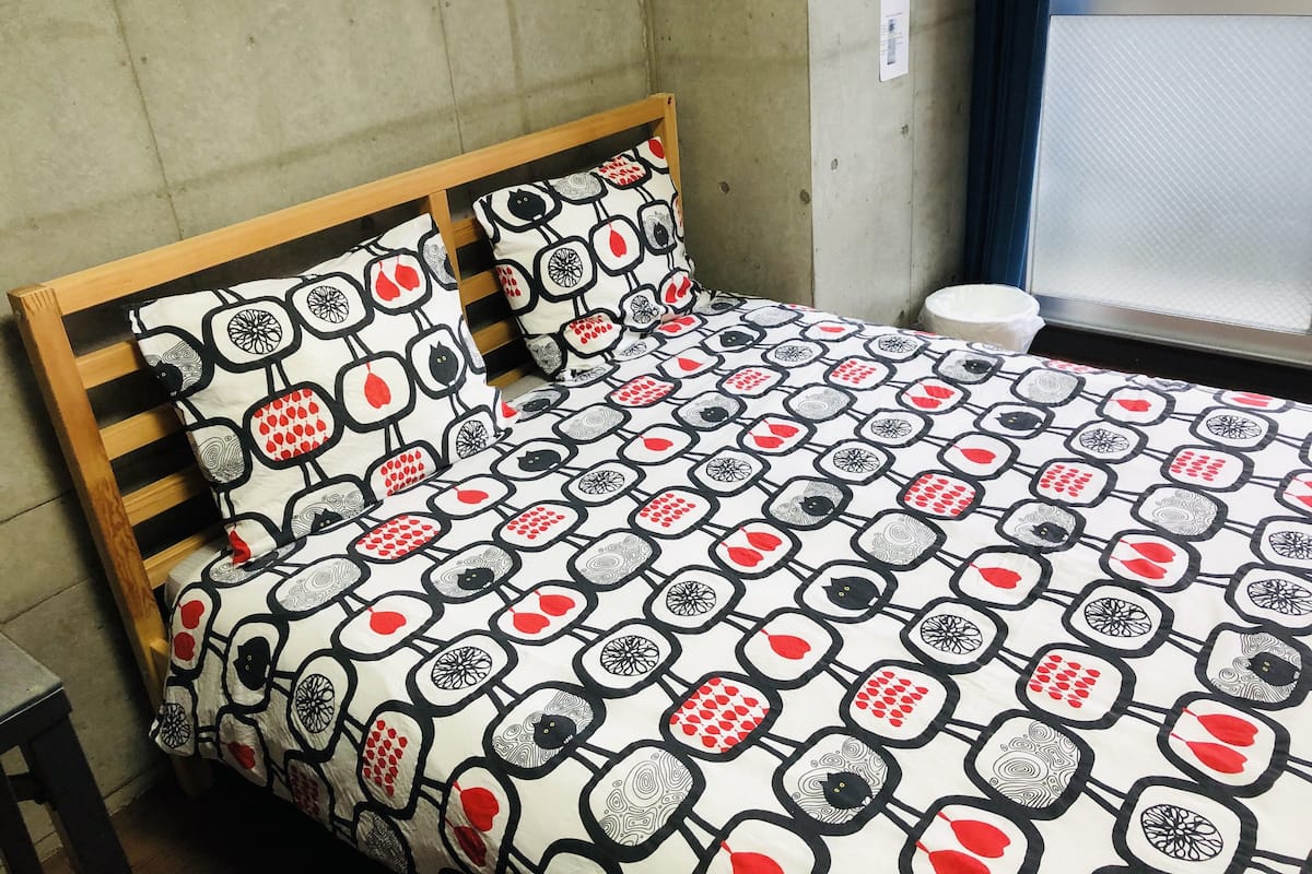 A bed with a patterned bedspread and matching pillows, a wooden headboard, and a window with a view of the outside.
