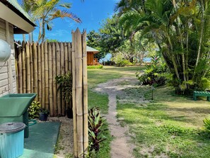 A garden with a bamboo fence, a pathway, and various plants.