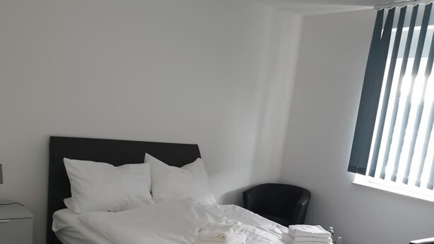 Een moderne slaapkamer met een groot bed, een nachtkastje en een stoel.