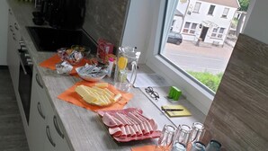 Een keuken met uitzicht door het raam, een spoelbak en verschillende etenswaren op het aanrecht.