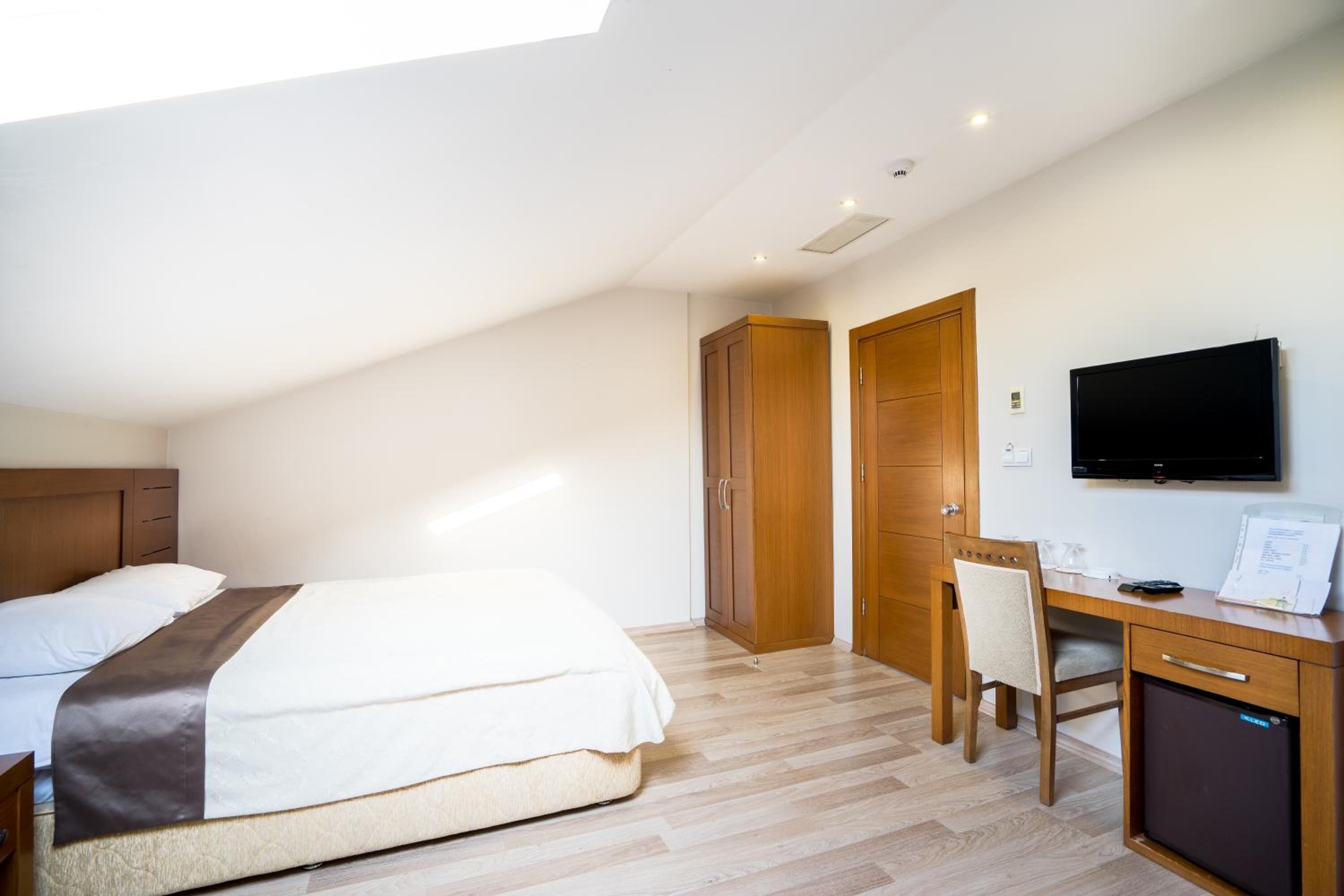 Un dormitorio con cama, escritorio, silla, televisor y armario.