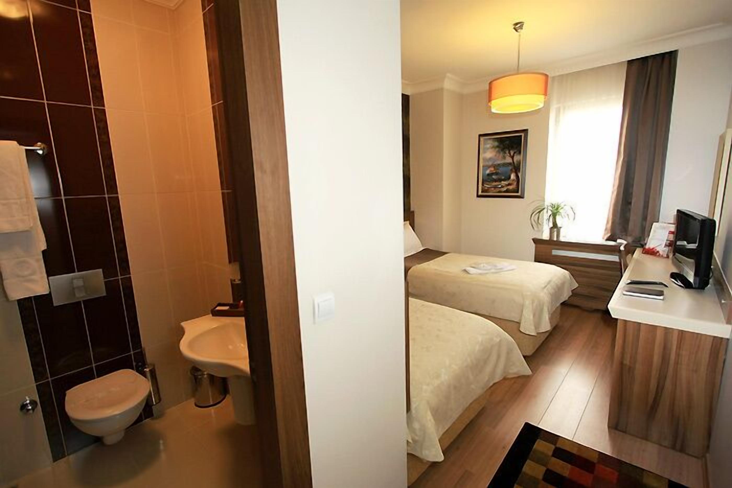 Une chambre d’hôtel avec salle de bain, deux lits, un bureau et un téléviseur.