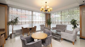 A modern lounge area with grey upholstered chairs, a round wooden table, and a chandelier. - My Rose Hotel (Istanbul)