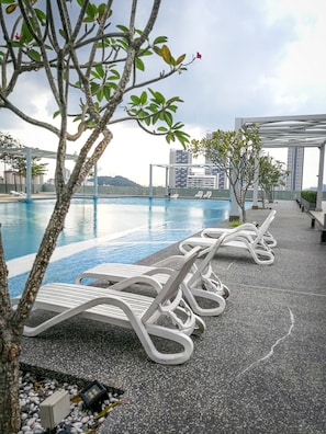 A rooftop pool area with lounge chairs and a pergola.
