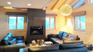 Ein modernes Wohnzimmer mit Ledersofas, einem Kamin und großen Fenstern.