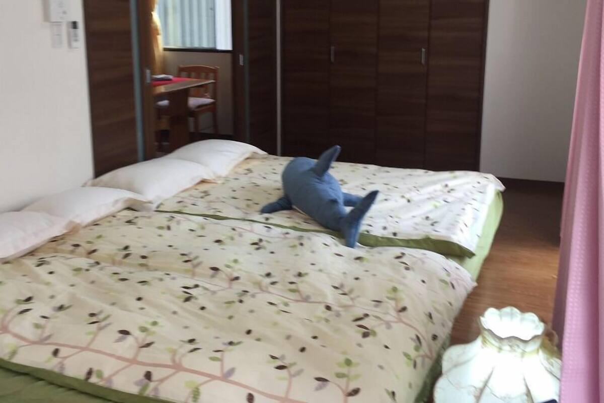 A bedroom with a bed, a desk, and a wardrobe.