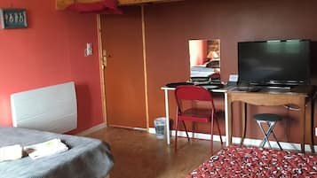 Et værelse med seng, skrivebord, stol og fjernsyn.