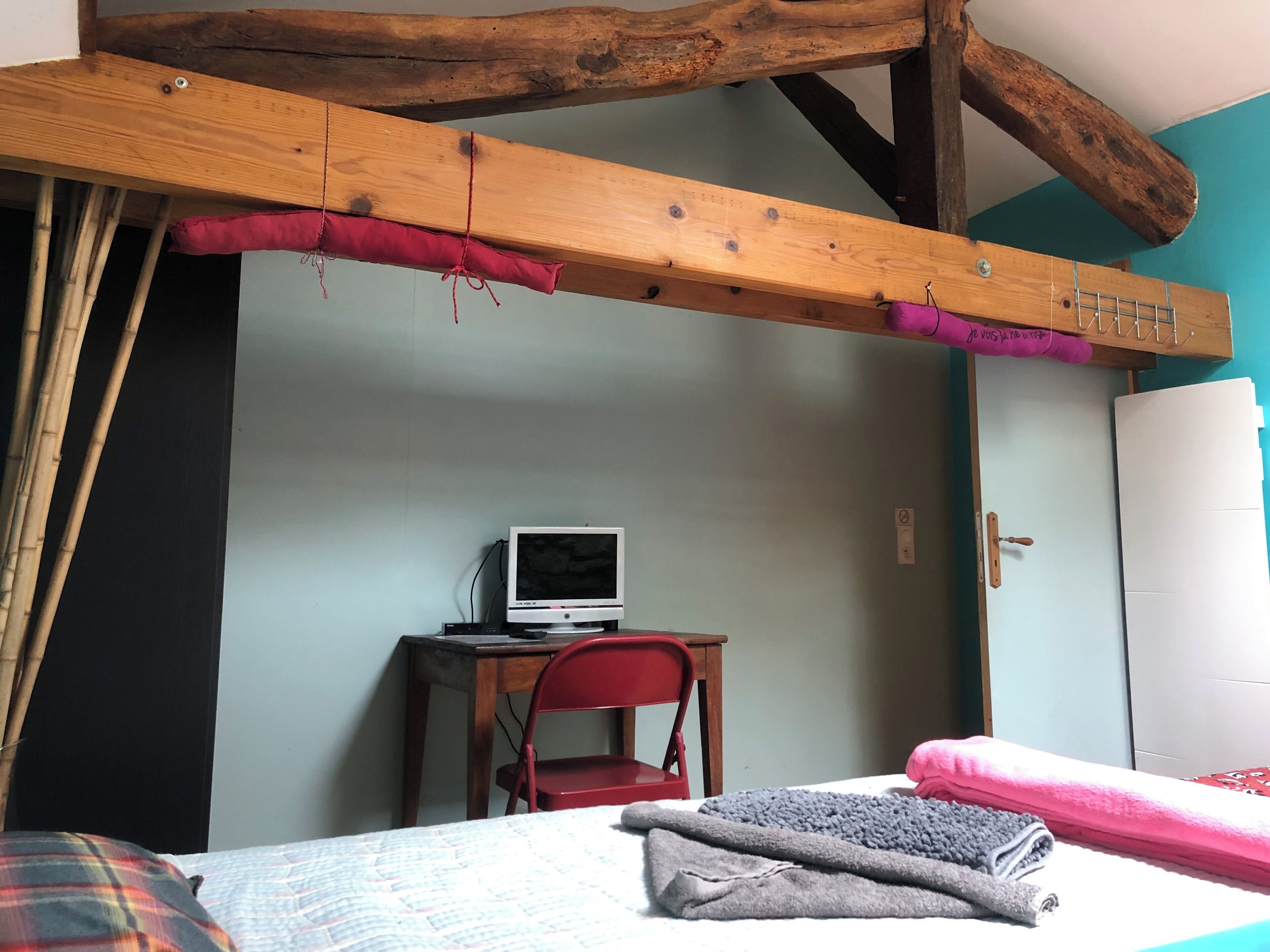 A room with a bed, a desk with a computer, a chair, and a wardrobe.