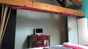 A room with a bed, a desk with a computer, a chair, and a wardrobe.