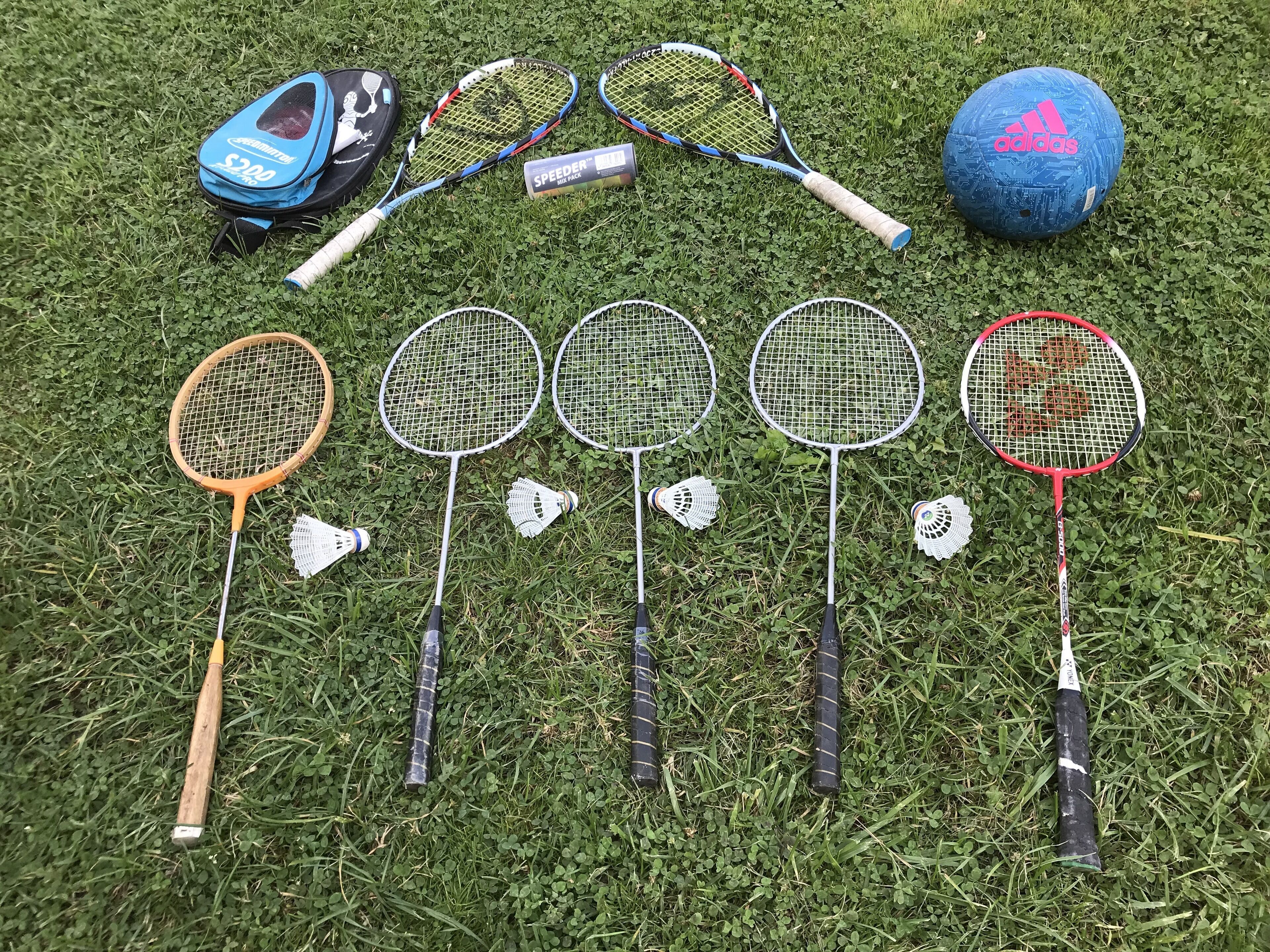 Badmintonketchere og fjerbolde arrangeret på græs.
