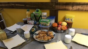 A breakfast table with croissants, fruits, milk, and various breakfast items. - Chambres Bambou & Corail & Music (Saint Sever)