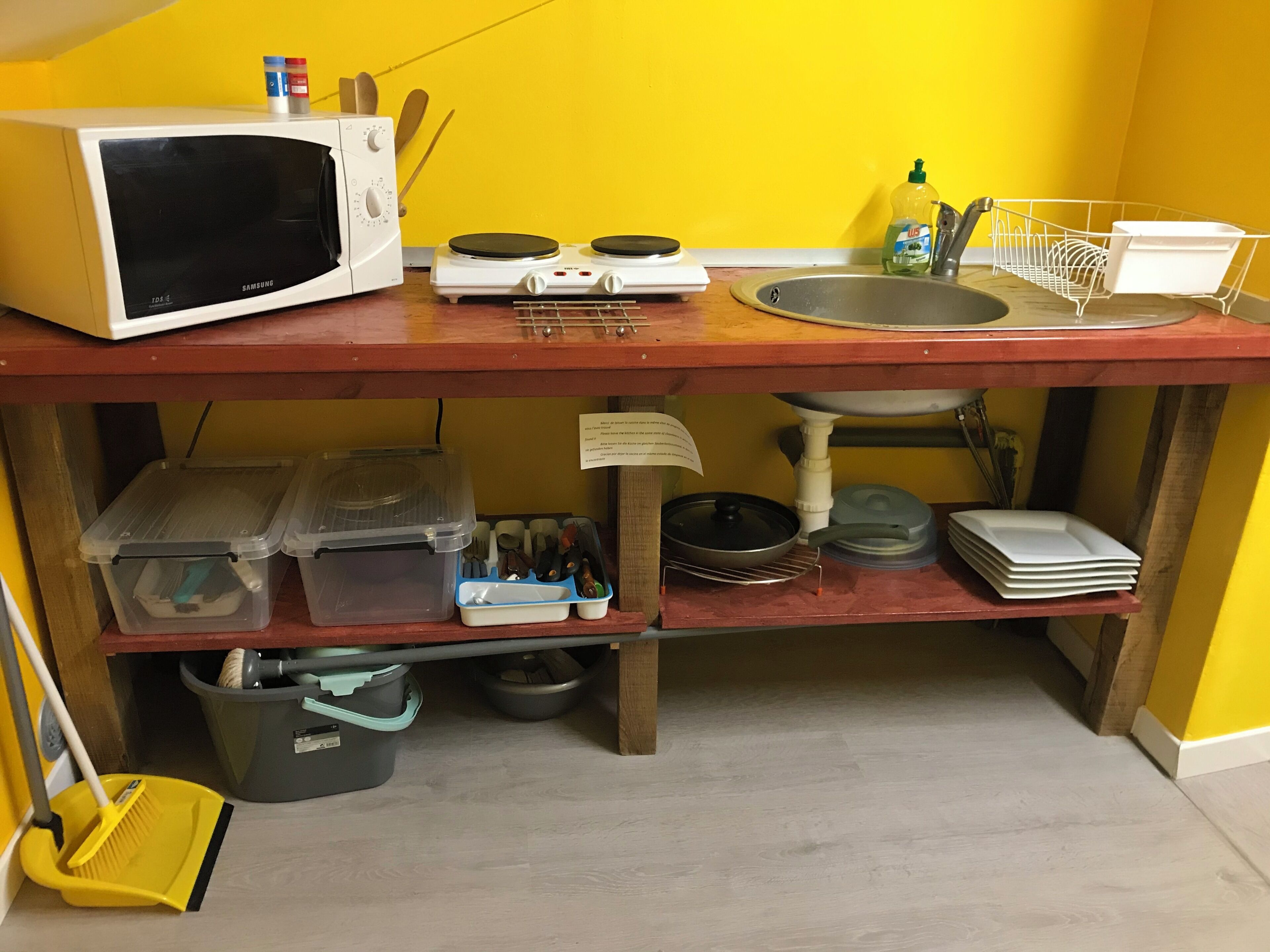 A kitchen area with a microwave, stove, sink, and various kitchen utensils and containers.