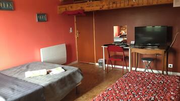 Une chambre avec deux lits, un bureau équipé d’un ordinateur et d’une télévision, une chaise et une structure de plafond en bois.