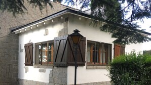 A stone building with a white facade, wooden shutters, and a central lantern.