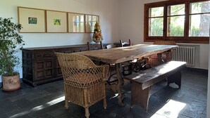 A dining area with a wooden table, wicker chairs, a bench, and a fruit tree decoration.