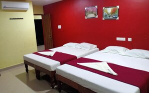 A hotel room with two beds, red walls, and two framed pictures. - Yelagiri Residency (Tirupattur)