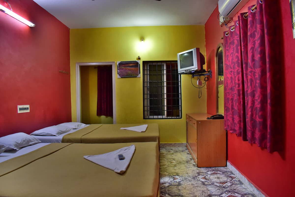 A room with two beds, a television, and a window with bars.