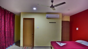 A hotel room with two beds, a ceiling fan, an air conditioning unit, and a door. - Yelagiri Residency (Tirupattur)