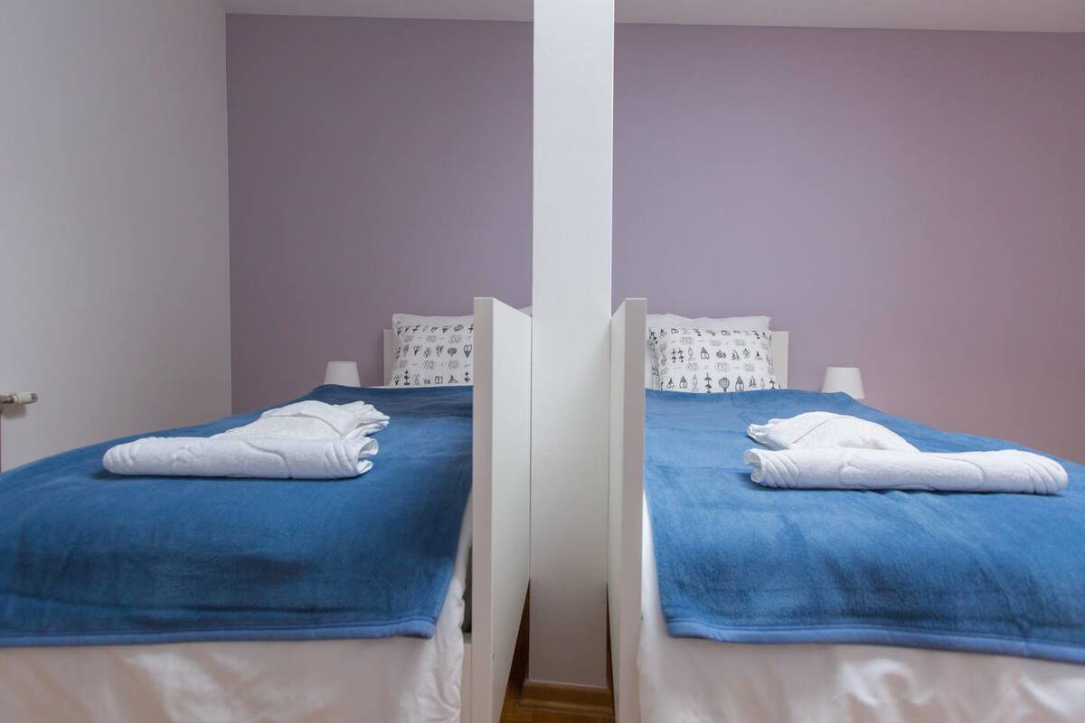 Two twin beds with blue bedding and white pillows, each with a folded white towel on top.