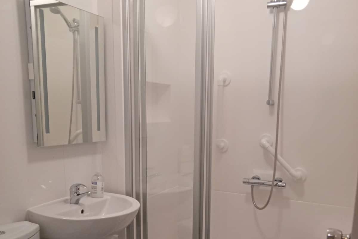 Une salle de bain avec une douche à parois de verre, un lavabo et des toilettes.