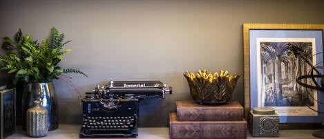 A vintage typewriter, a framed picture, and decorative items on a shelf.