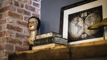 A brick wall, a globe map, and a bust sculpture on a wooden shelf.