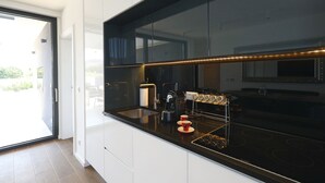Una cocina moderna con encimera negra, electrodomésticos de acero inoxidable y una cafetera.