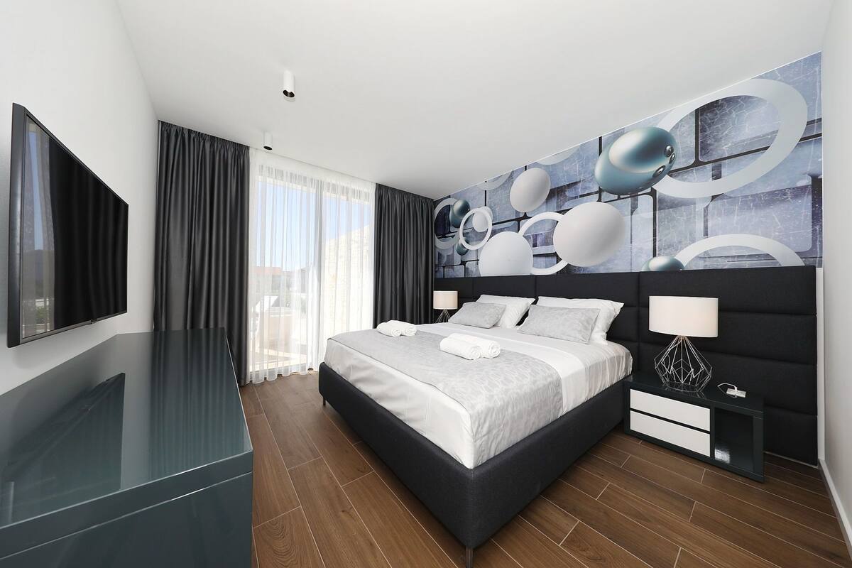 Una camera d'albergo moderna con un letto grande, una TV a schermo piatto e vista sulla città.