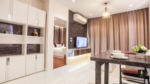 Ein modernes Hotelzimmer mit Marmor-Waschtisch, Fernseher, Essbereich mit Marmortisch und einem großen Fenster mit Vorhängen.