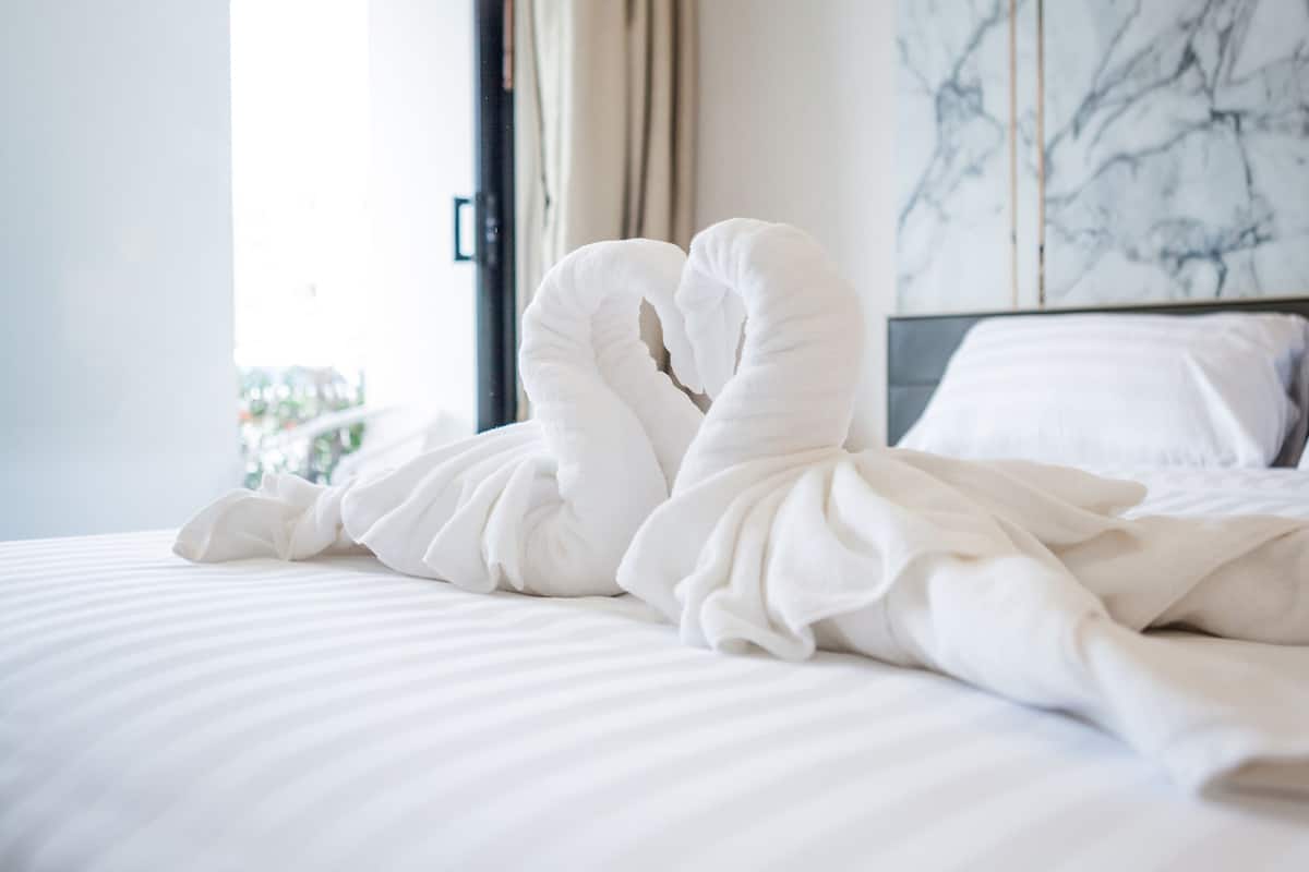 Een bed met witte beddengoed en een handdoekarrangement in de vorm van een zwaan.