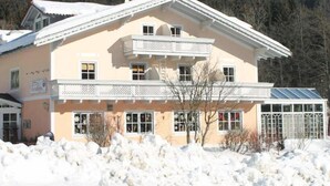 Un bâtiment à deux étages doté d’un balcon et d’un porche couvert, entouré de neige.