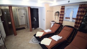 Une salle de spa équipée de deux tables de massage, d’un espace douche et d’une statue murale.