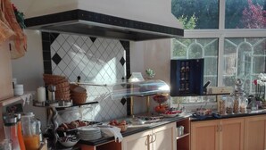 Une cuisine avec un bar pour prendre le petit-déjeuner, un coin repas avec une table et des chaises, et une vue dégagée grâce à de grandes fenêtres.
