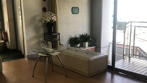 A reception area with a glass table, a sofa, and potted plants. - Business Hotel Nakayama (Nagoya)