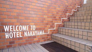 A brick wall with a sign reading "WELCOME TO HOTEL NAKAYAMA" and a set of stairs leading up to it. - Business Hotel Nakayama (Nagoya)
