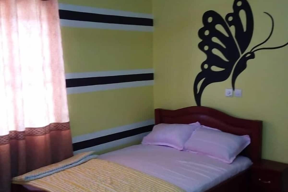 Une chambre à coucher comprenant un lit, une table de chevet, un élément de décoration murale et un tapis en forme de pied.